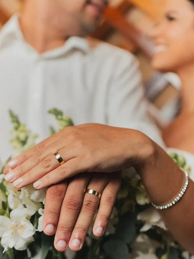 Casal exibindo alianças de casamento Ouro Fino em ouro 18k